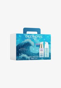 Deep Dive Hydration Set æske med to hudplejeflasker mærket Good Genes og Tidal, med et pixeliseret bølgedesign i blå nuancer.