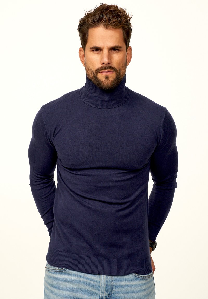 Dunkelblauer Rollkragenpullover, gerippter Halsausschnitt und Bündchen, schlanke Passform, weiche Textur, getragen mit hellblauen Jeans. Einfacher und klarer Look.