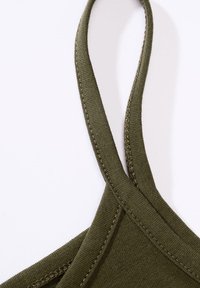 Oliwkowo zielona tkanina na ramiączka spaghetti z płaskimi szwami i gładką teksturą. Ramiączko jest wąskie i ma jednolity wzór.