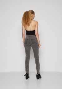 Γκρι παντελόνι ψηλής μέσης σε στενή γραμμή, με δύο πίσω τσέπες και αντίθετα ραφά, συνδυασμένο με μαύρες ψηλές γόβες.