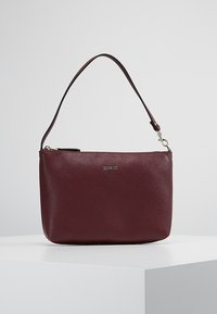 Bordeauxrode leren handtas met een gestructureerde afwerking, ritssluiting en een enkele verstelbare schouderriem. Voorzien van een gouden logodetail.