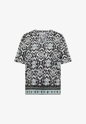 Černobílá halenka s krátkým rukávem se světle modrými abstraktními geometrickými vzory, výstřihem do V se střapcovými šňůrkami a dekorativním lemem na spodním okraji.