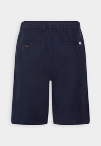 Shorts homme bleu marine avec poches arrière à boutons, taille élastique, passants pour ceinture et petite étiquette de marque blanche sur le côté droit.