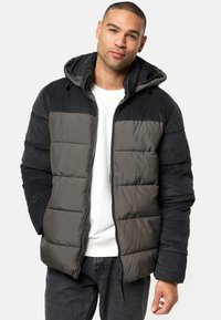 Puffer jacket featuring a black corduroy upper, gray quilted body, and adjustable hood. The design includes front pockets and a zipper.