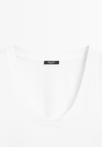 Witte T-shirt met ronde hals en een zwart label waarop 'Massimo Dutti Made in India' staat, aan de binnenkant van de achterkant van de hals genaaid.