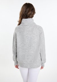 Lichtgrijze, oversized trui met hoge kraag, ribbelstructuur en een zachte stof. Heeft een verlaagde schouderlijn en een ontspannen pasvorm.