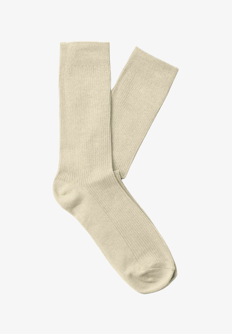 Paire de chaussettes unies beige clair à bord-côtes, posées à plat et superposées sur fond blanc.