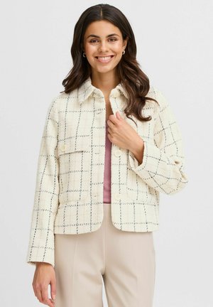 Cream-colored jacket with a textured fabric, featuring a black grid pattern, button closure, and two front pockets. Casual, boxy design.