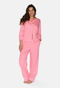 Set di pigiama rosa realizzato in tessuto morbido, composto da una camicia con bottoni e maniche lunghe e pantaloni a gamba larga coordinati. Accentuato con dettagli bianchi.