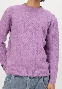 Violetti palmikkoneulepaita, jossa on resorireunainen kaulus ja helma. Pehmeä rakenne, jossa erilaisia neulomismalleja. Päällä vaaleiden farkkujen päällä.