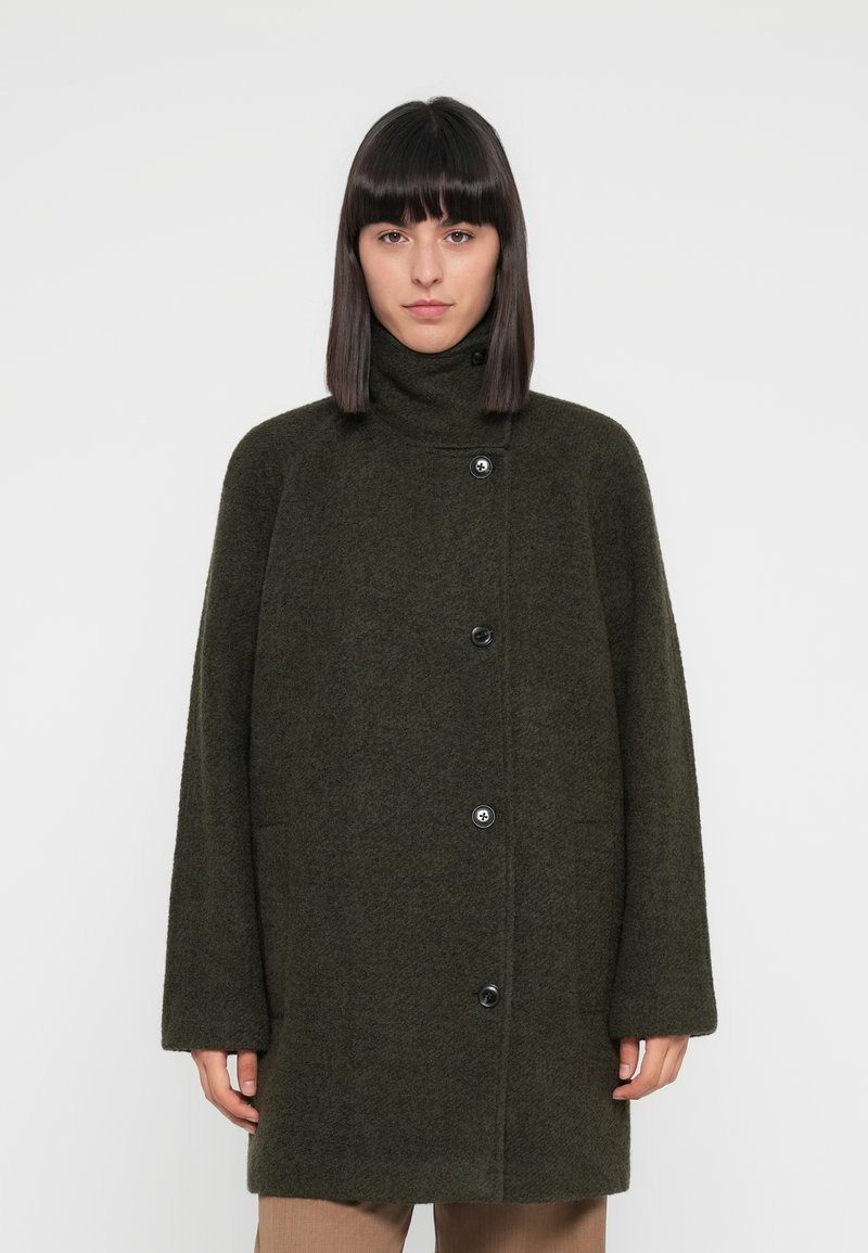 Olive green wool coat with a high collar, oversized fit, and black buttons. Features long sleeves and a soft, textured finish.