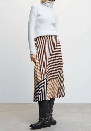 Gestreifte Midi-Rock in Braun, Creme und Schwarz mit geometrischen Mustern. Kombiniert mit einem weißen, gerippten Rollkragenpullover und schwarzen Stiefeln.