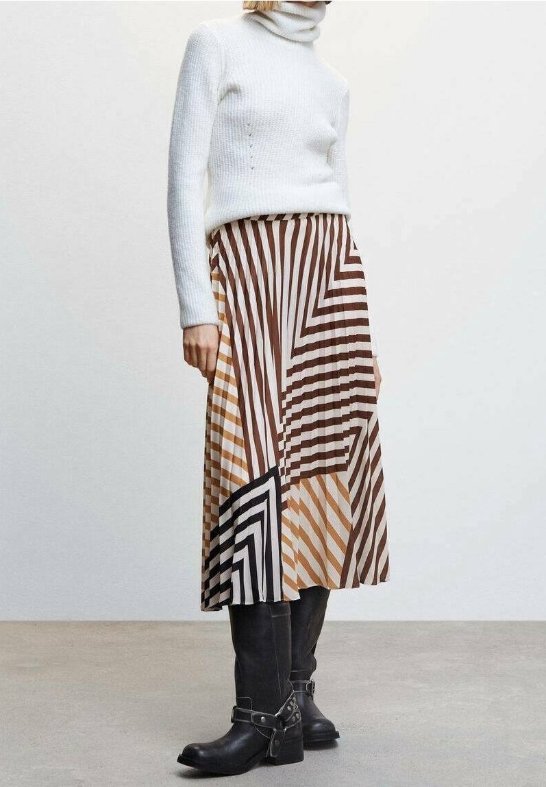 Jupe midi rayée en marron, crème et noir, avec des motifs géométriques. Assortie à un pull col roulé côtelé blanc et des bottes noires.
