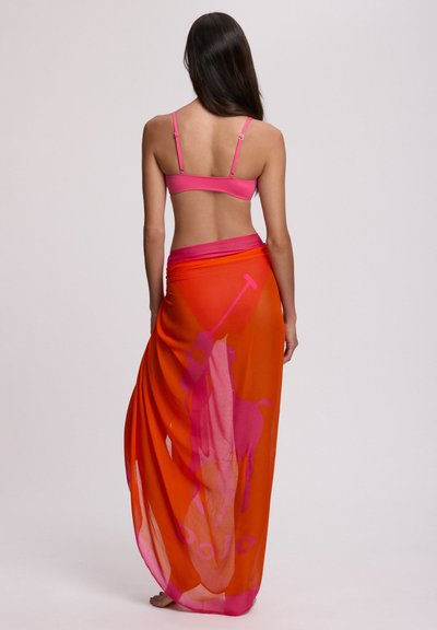 Ροζ μπικίνι τοπ συνδυασμένο με διαφανές πορτοκαλί σάρονγκ. Το σάρονγκ έχει ορατό ροζ λογότυπο και γραφικό με αναβάτη αλόγου, σχεδιασμένο με ρέουσα υφή.