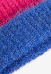 Strikket stof med en levende pink sektion over en struktureret blå sektion, med en blød og fluffy tekstur samt et ribbet mønster over det hele.