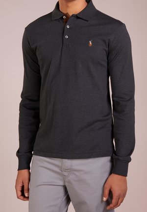 Mann trägt ein dunkelgraues Langarm-Poloshirt mit kleinem, auf der Brust gesticktem Logo und hellgraue Hose.