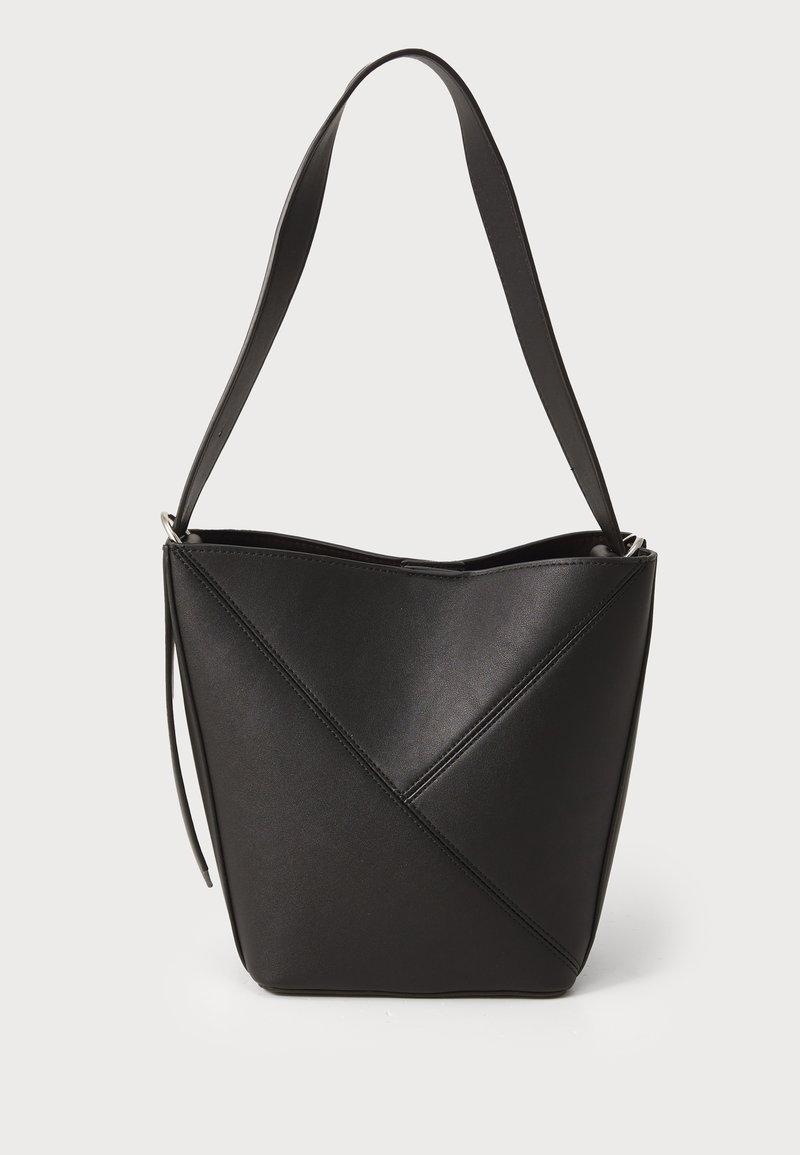 Saco de couro preto em forma de balde com um design de costura diagonal, alça única para o ombro e abertura no topo, apresentando uma textura suave.