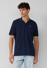 Navyblauwe polo in katoenstof met een v-hals, korte mouwen, een zak op de linker borst en subtiele logodetail.