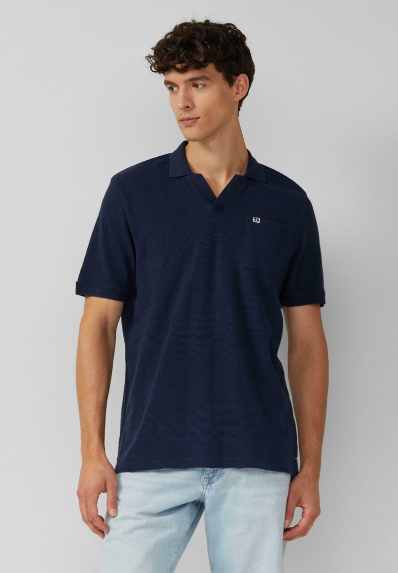 Navyblauwe polo in katoenstof met een v-hals, korte mouwen, een zak op de linker borst en subtiele logodetail.
