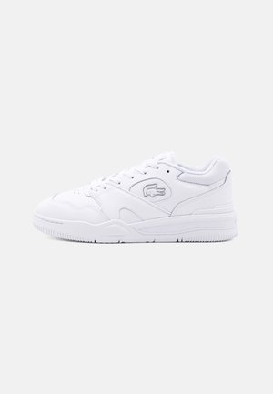 White low-top sneaker with lace-up design, rubber sole, mesh collar, and embossed crocodile logo on the side.