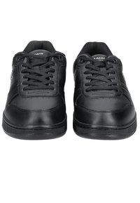 Paire de baskets en cuir noir Lacoste avec lacets noirs, vue de face, montrant les détails des coutures et le logo de la marque sur la languette et le côté.