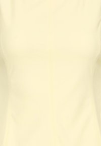 Vêtement ajusté sans manches de couleur crème avec des lignes de couture visibles à l'avant et sur les côtés.