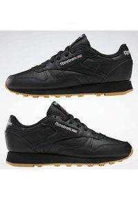 Čierne kožené tenisky s okrúhlou špičkou a gumovou podrážkou. Medzi funkcionality patrí polstrovaný golier, šnurovací dizajn a značka Reebok na boku.