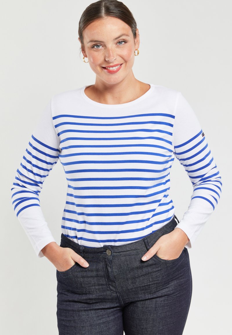 T-shirt a maniche lunghe con righe orizzontali blu e bianche, scollatura rotonda e tessuto morbido. Indossato con pantaloni in denim scuri.