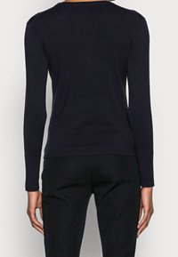 Schwarzes Langarmtop mit figurbetontem Schnitt, Rundhalsausschnitt und glattem Strickstoff, kombiniert mit schwarzen Hosen. Keine sichtbaren Marken oder Muster.