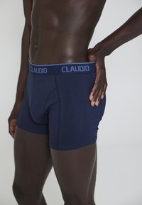 Pantaloni boxer blu navy in cotone, con una cintura morbida e la scritta "CLAUDIO". Texture liscia e design aderente.