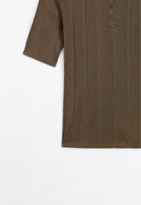 Polo shirt marron à manches courtes avec texture ribbed verticale, patte de boutonnage à quatre boutons et ourlet droit. Fabriqué en tissu tricot doux.