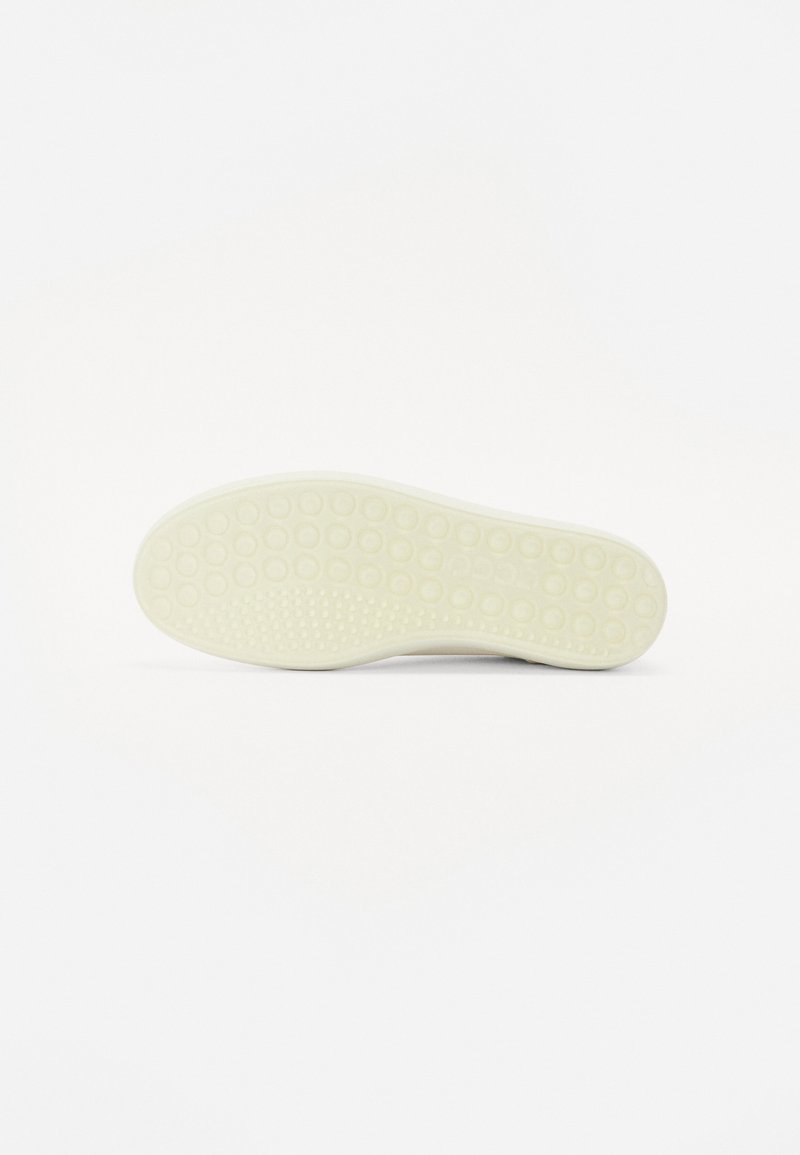 Spódnica sportowego buta w białej gumie z okrągłym wzorem przyczepności, z gładką powierzchnią i zaokrąglonym kształtem, na jasnym tle.