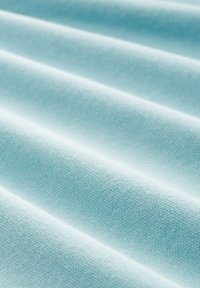 Light blue fabric with a textured surface, displaying soft, pleated folds. The material has a smooth finish and subtle weaves throughout.