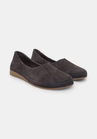Pantofi slip-on din suede negru cu vârful rotunjit, toc mic și detalii simple de cusătură pe lângă cusături. Textură moale, design minimalist.