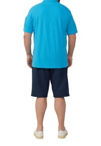 Niebieska koszulka polo z krótkim rękawem, z kołnierzykiem, w połączeniu z ciemnonawigacyjnymi szortami. Strój ma luźny krój i lekki materiał.