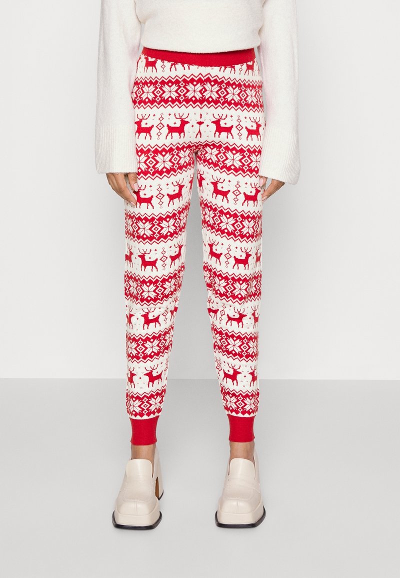 Czerwono-białe spodnie dresowe w wzory z motywami reniferów, geometrycznymi desenami oraz ściągaczem w talii; wykonane z miękkiego, teksturowanego materiału.
