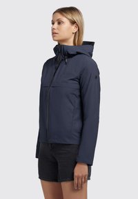 Marineblauwe hoodie gemaakt van lichtgewicht materiaal, voorzien van een ritssluiting, voortassen en het merkimaar op de borst en mouw.