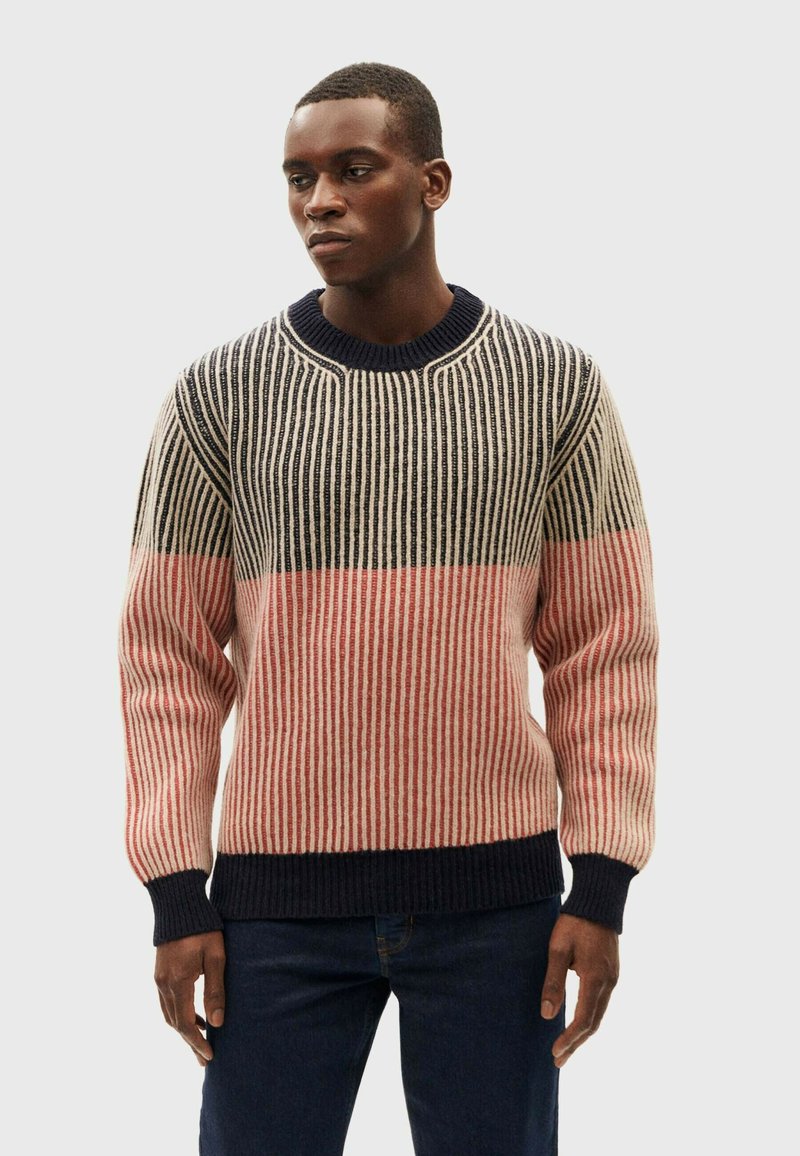 Knit sweater featuring horizontal stripes in navy, cream, and coral. Ribbed crew neckline and cuffs with textured fabric. Casual fit.