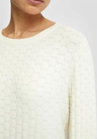 Sweter w kolorze kremowym z teksturowanym, okrągłym wzorem, z okrągłym dekoltem i miękkim wykończeniem dzianinowym. Prosty i lekki design.
