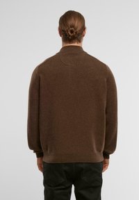 Brauner Strickpullover mit lockerer Passform, hohem Kragen und gerippten Bündchen. Weiche Textur und einfarbig, mit einem nahtlosen Rückendesign.