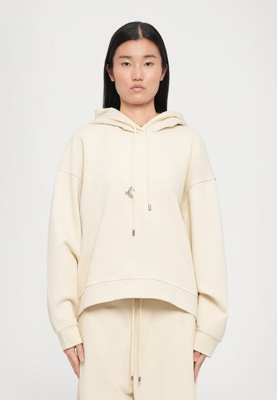 Lichtbeige hoodie gemaakt van zachte stof, met een relaxte pasvorm, oversized mouwen en trekkoorden bij de capuchon.