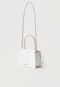 Λευκή τσάντα χειρός σε σχήμα τραπεζίου με λαβή κορυφής διακοσμημένη με μαργαριτάρια και λεπτή ασημί αλυσίδα ώμου, τοποθετημένη σε λευκό φόντο.