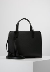 Borsa nera dal design strutturato. Realizzata in materiale testurizzato, dotata di manici corti e tracolla staccabile con un dettaglio a nappina.