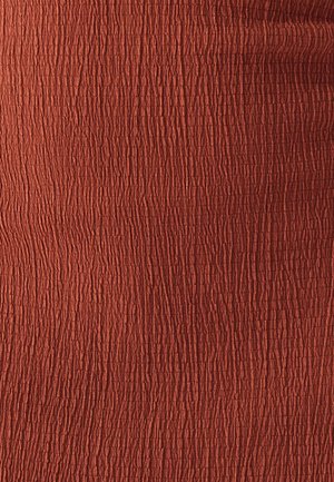 Tejido texturizado en un color óxido profundo, con un patrón arrugado que añade detalle táctil e interés visual.