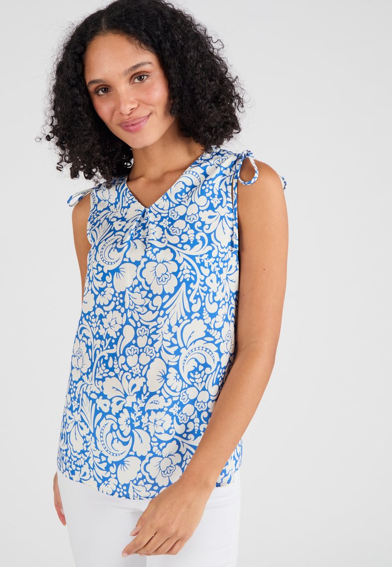 Top senza maniche blu e bianco con stampa floreale, scollatura a V e spalline annodate, realizzato in tessuto leggero con una finitura liscia.