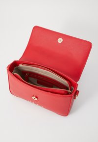 Borsa a tracolla in pelle sintetica rossa con scomparto con zip, accessori in tonalità oro e texture liscia. Il flap aperto mostra un interno organizzato.