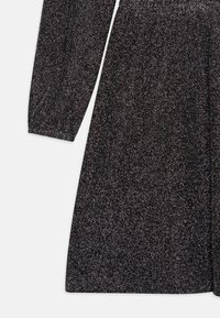 Vestido preto com mangas longas, feito de um tecido texturizado cintilante. Apresenta uma cintura elástica e uma silhueta em linha A fluida.