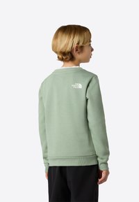 Zelená mikina z mäkkého materiálu s rebrovanými manžetami a lemom. Na zadnej strane je biele logo a okrúhly výstrih s vnútornou vrstvou.