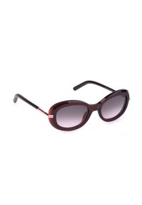 Lunettes de soleil ovales marron foncé avec verres teintés en dégradé et fines branches noires, légèrement inclinées sur un fond blanc.