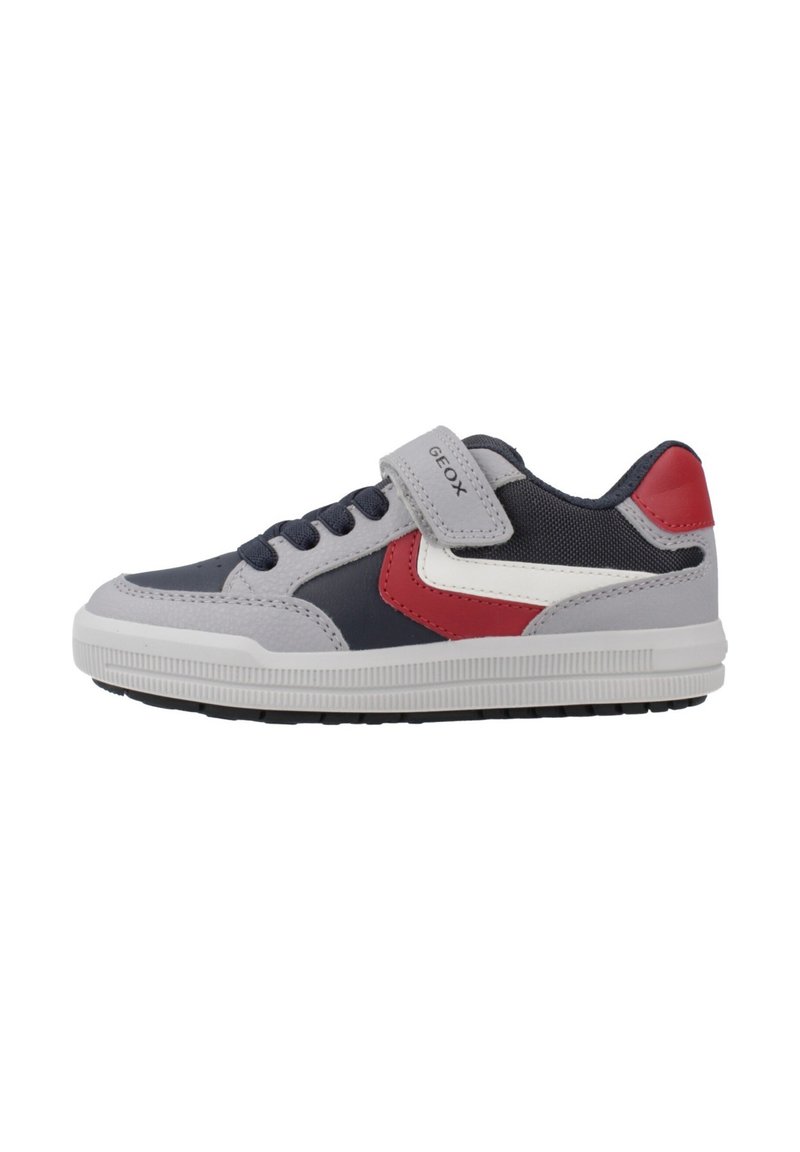 Zapatilla infantil en azul marino, gris, rojo y blanco con cordones y una correa de Velcro etiquetada "GEOX", con surcos en la suela lateral y un diseño de caña baja.